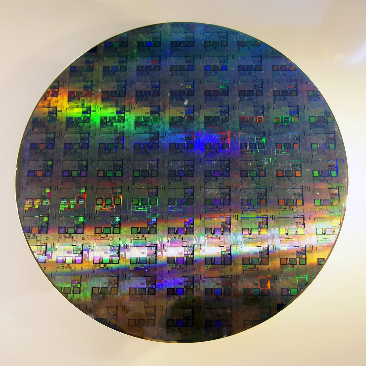 A 12-inch silicon wafer, its surface showing an iridescent grid of etched chips